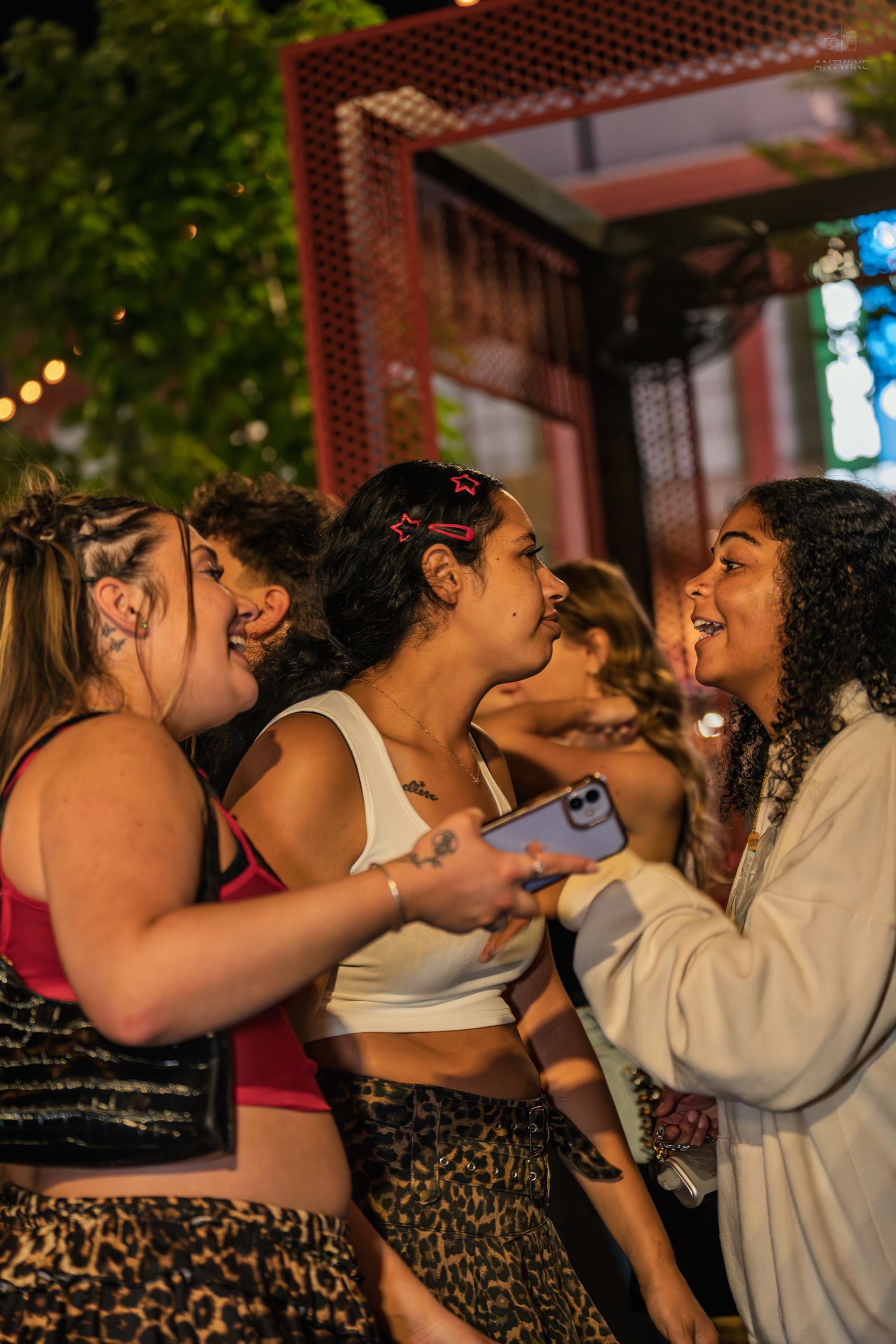 Three young women laughing and socializing together at an outdoor nighttime party event.