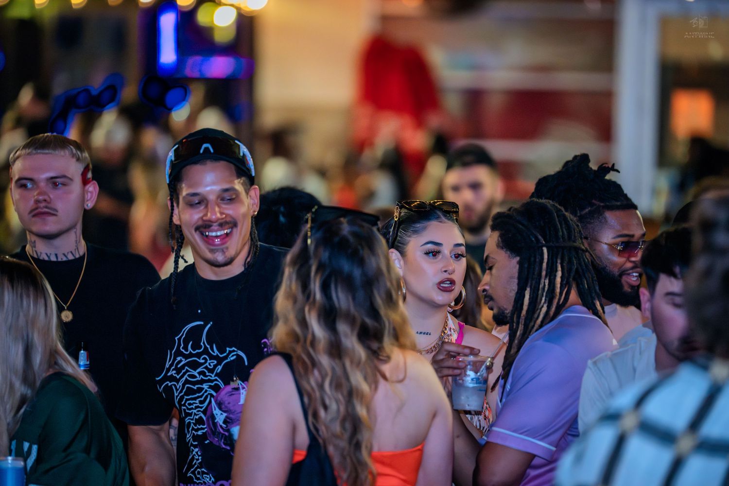 Diverse group of people laughing and socializing at a lively nightclub party event.