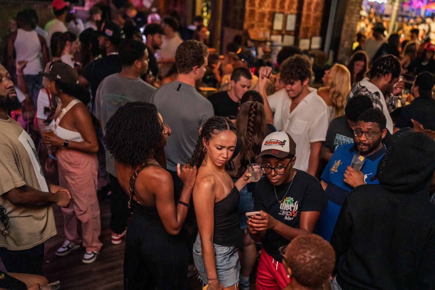 Young adults mingling and socializing at a lively indoor nightclub party.