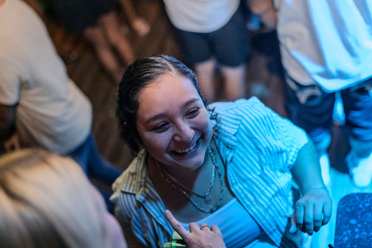 Smiling young woman with wet hair enjoying herself at a crowded nightclub party.