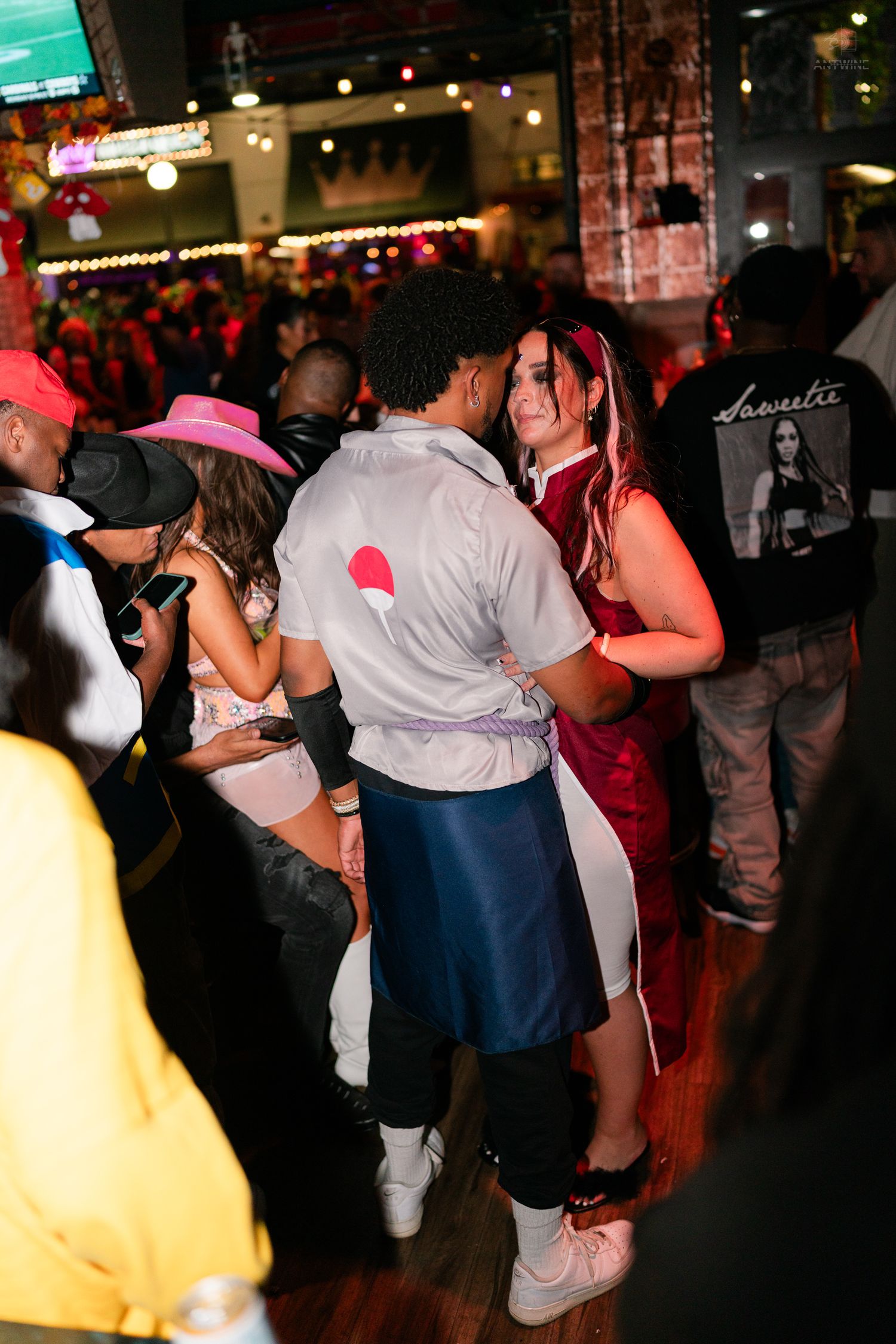 Couples dancing in Halloween costumes at a crowded indoor nightclub Halloween party event.