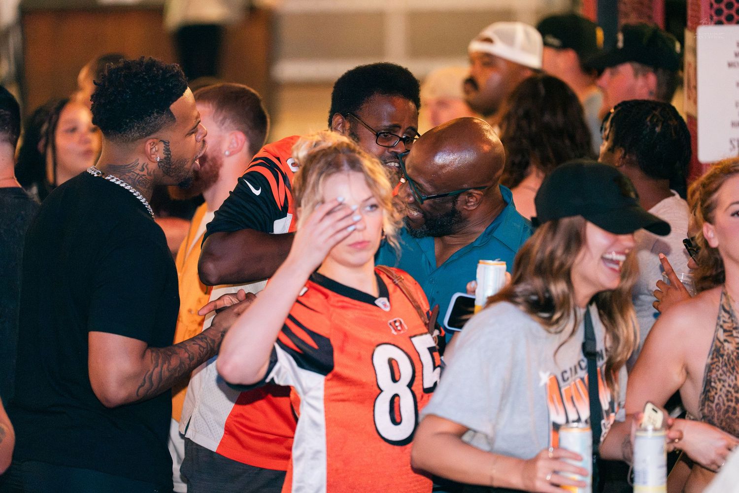 Woman in Bengals jersey at a crowded sports bar watch party event.