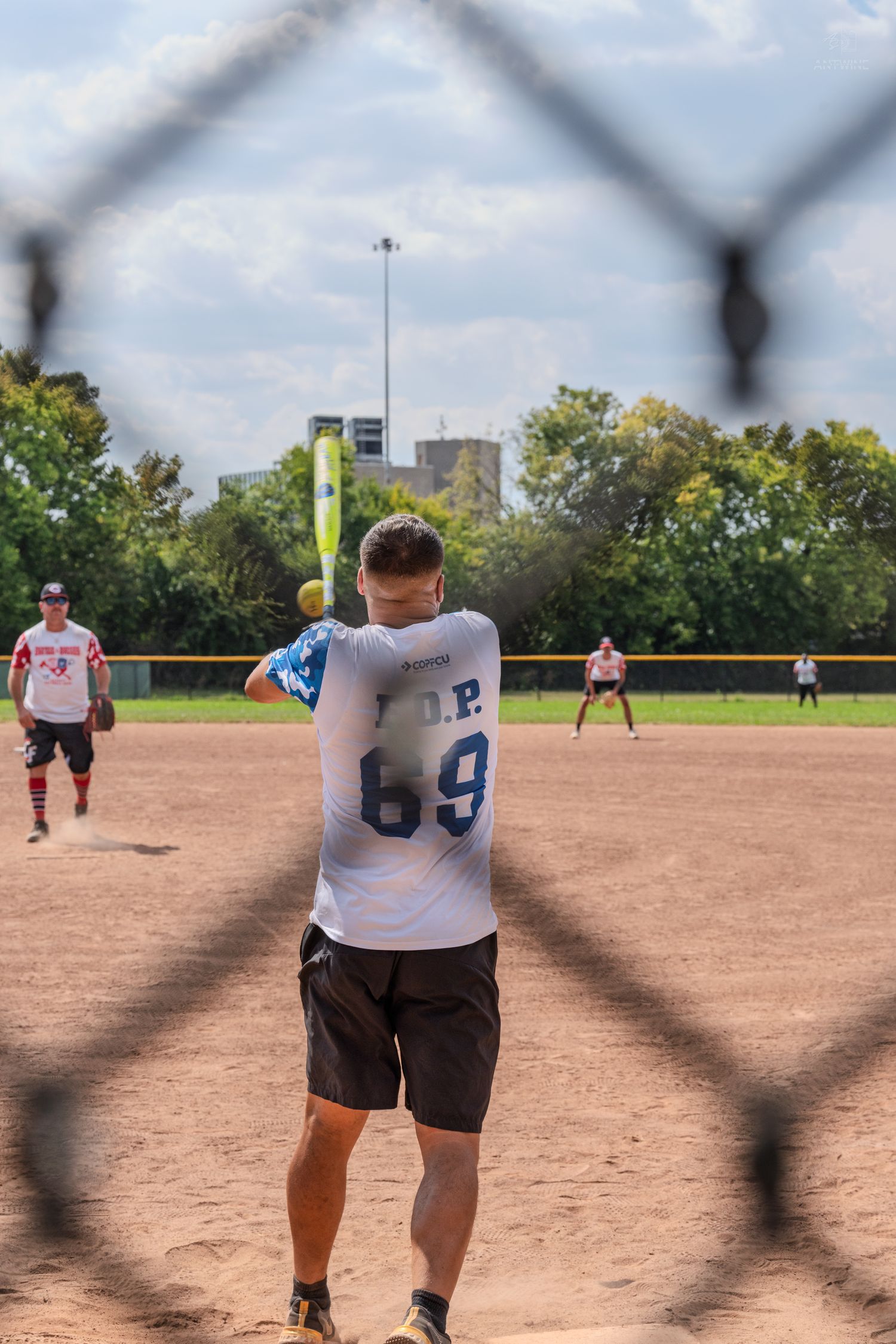 F.O.P. #69 player makes contact with a yellow softball during an outdoor recreational game.