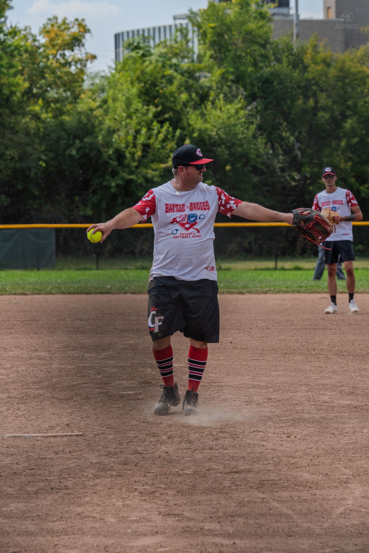 A softball pitcher prepares to throw a yellow ball during a Battle of Badges charity game.