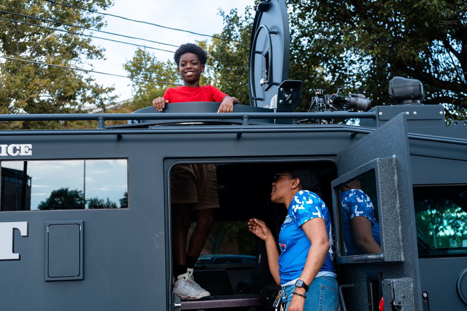 Kids explore a police SWAT armored vehicle during a community outreach event outdoors.