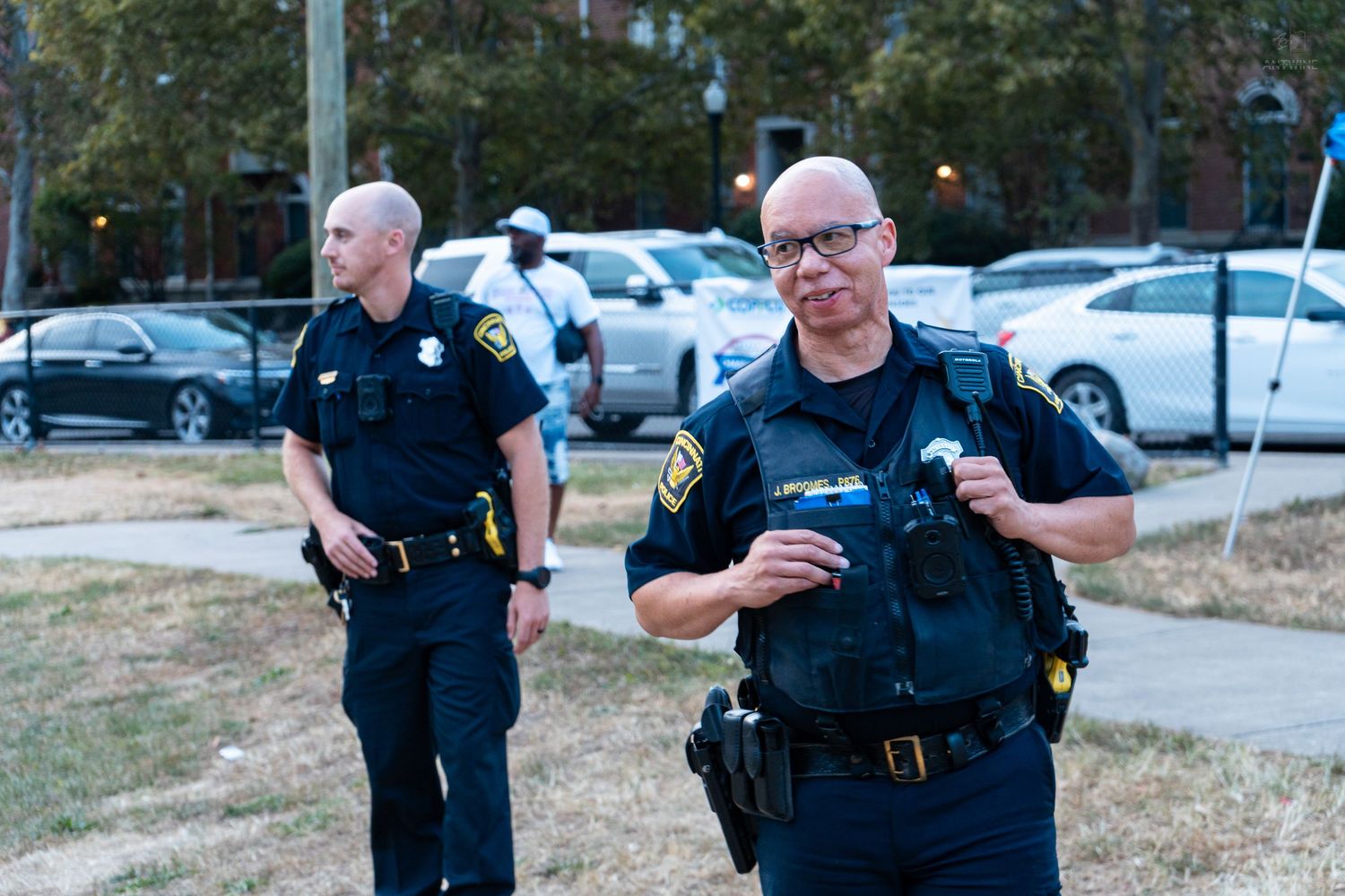 Two police officers in uniform standing outdoors on alert at an incident scene.