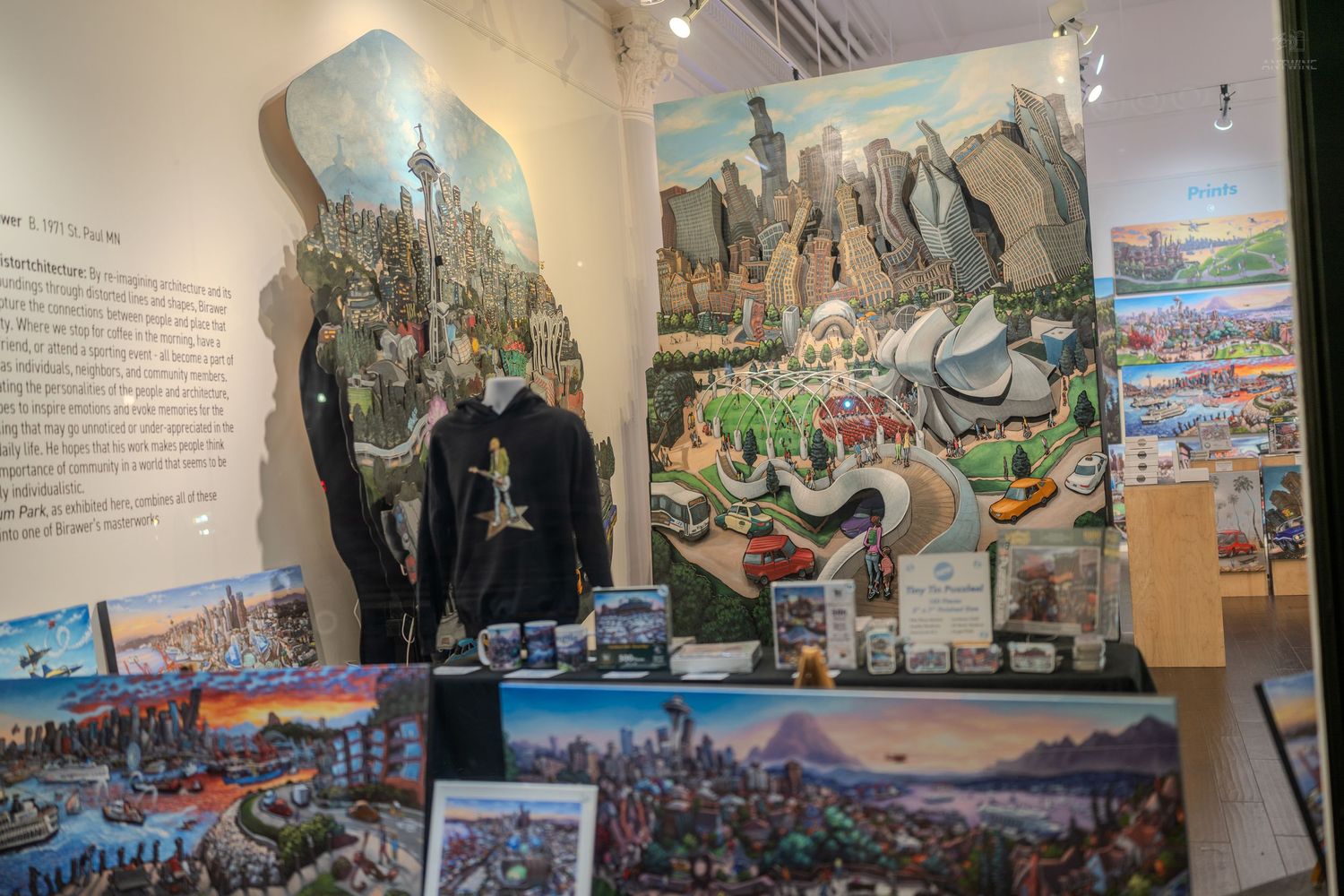 Colorful panoramic artwork and souvenirs displayed in a gift shop with cityscape paintings on the wall.