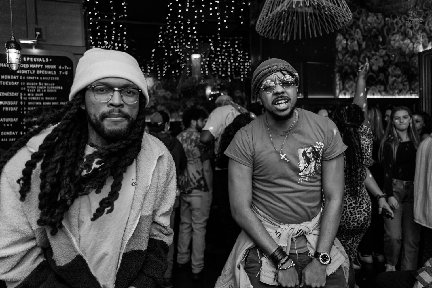 Two men posing together at a nightclub event in black and white photography.