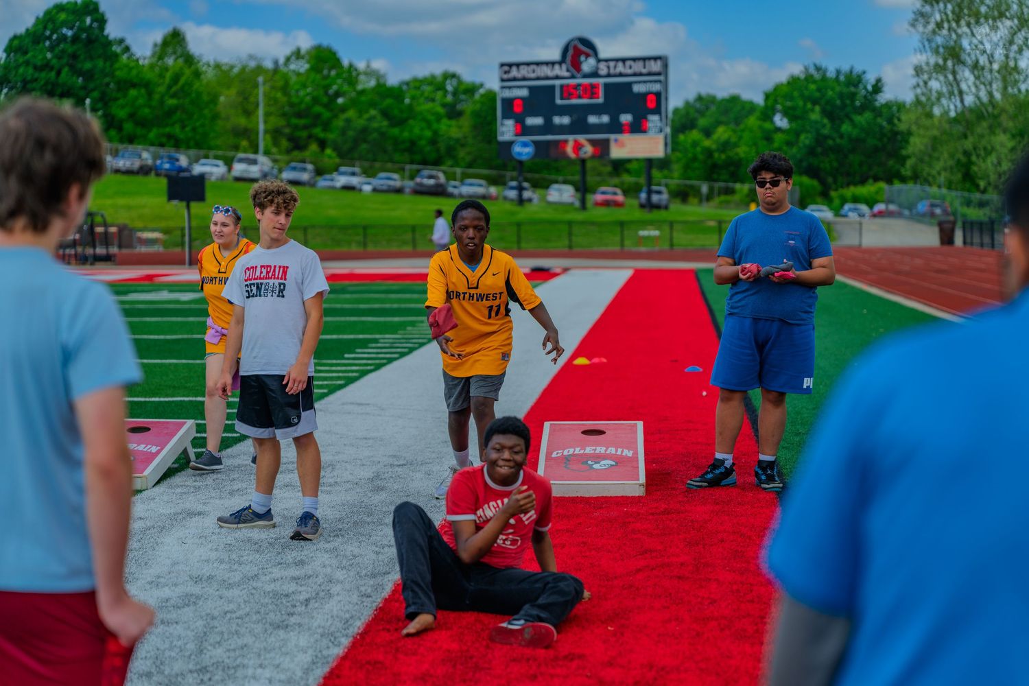Students enjoy outdoor activities on a red carpet at Cardinal Stadium track and field on a sunny day.