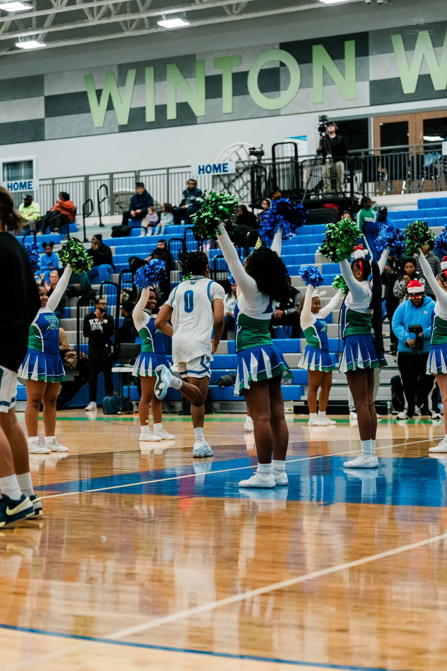 Cheerleaders in blue and green uniforms perform at Winton Woods gym.