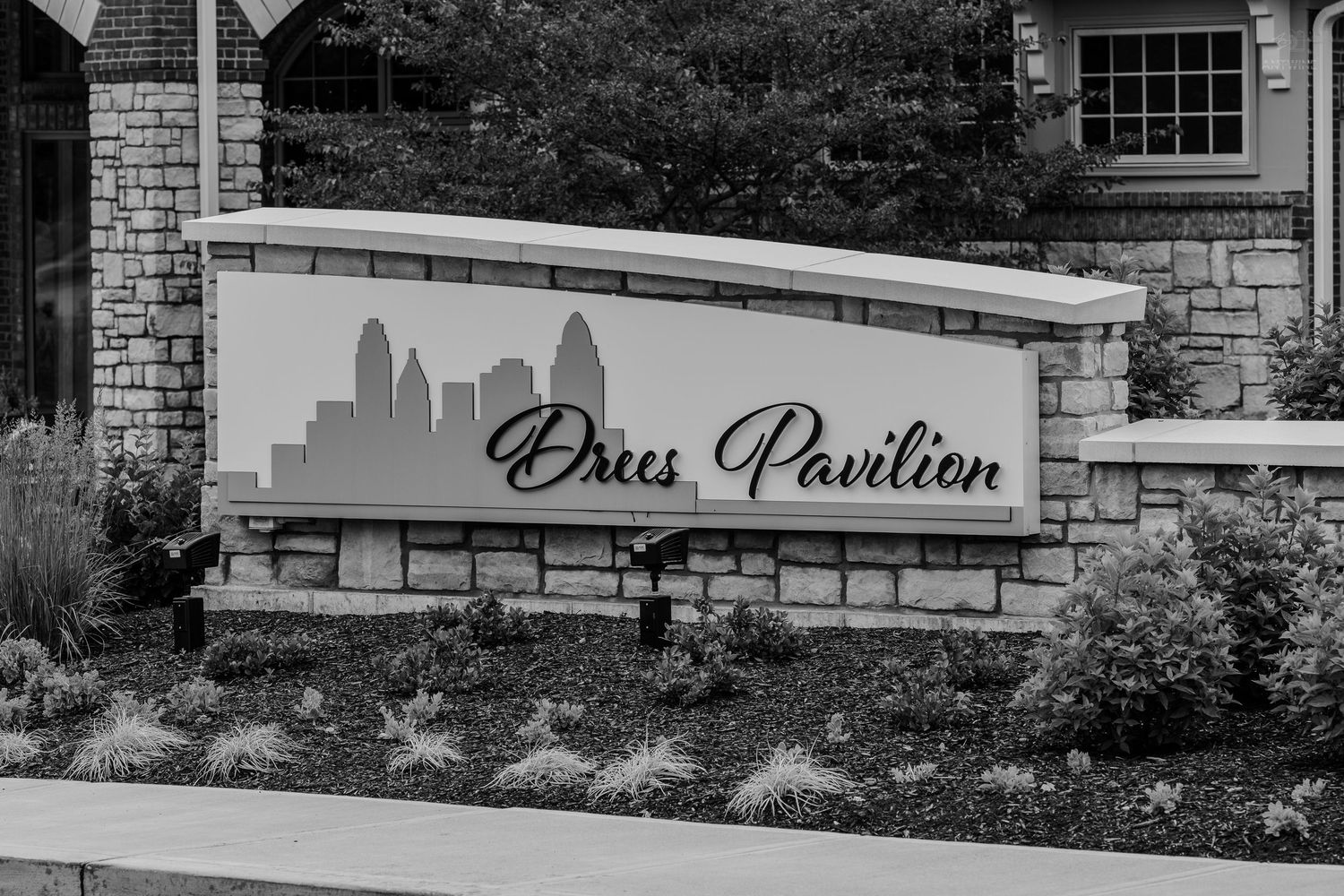 Drees Pavilion stone entrance sign with Cincinnati skyline logo in black and white photo.