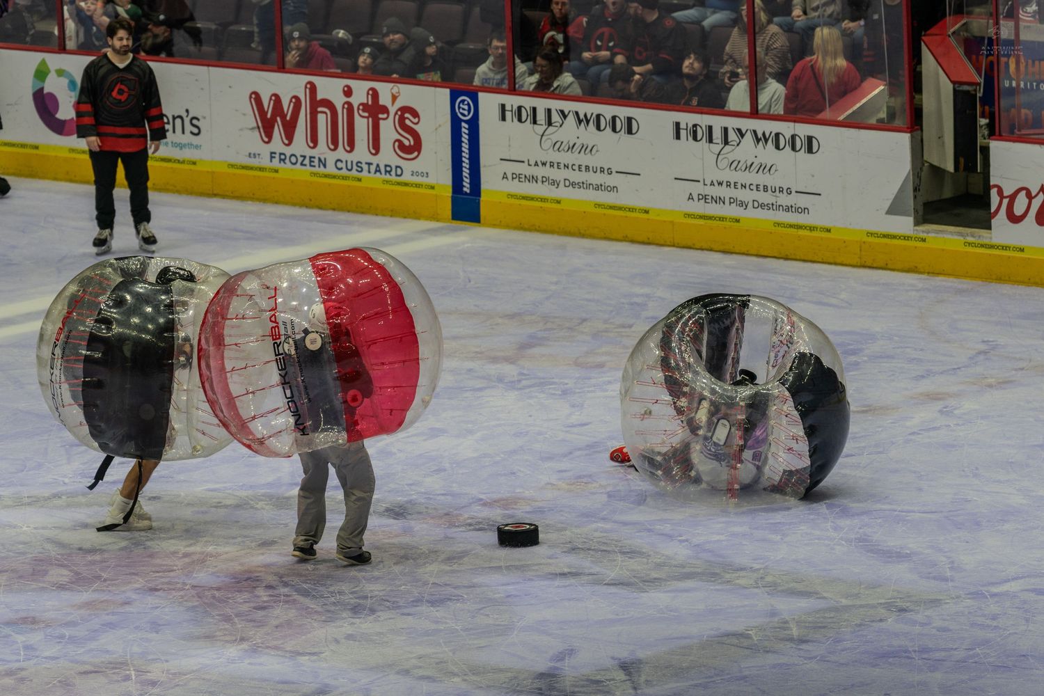 Two players in inflatable bubble soccer balls collide on an ice rink during an intermission activity.