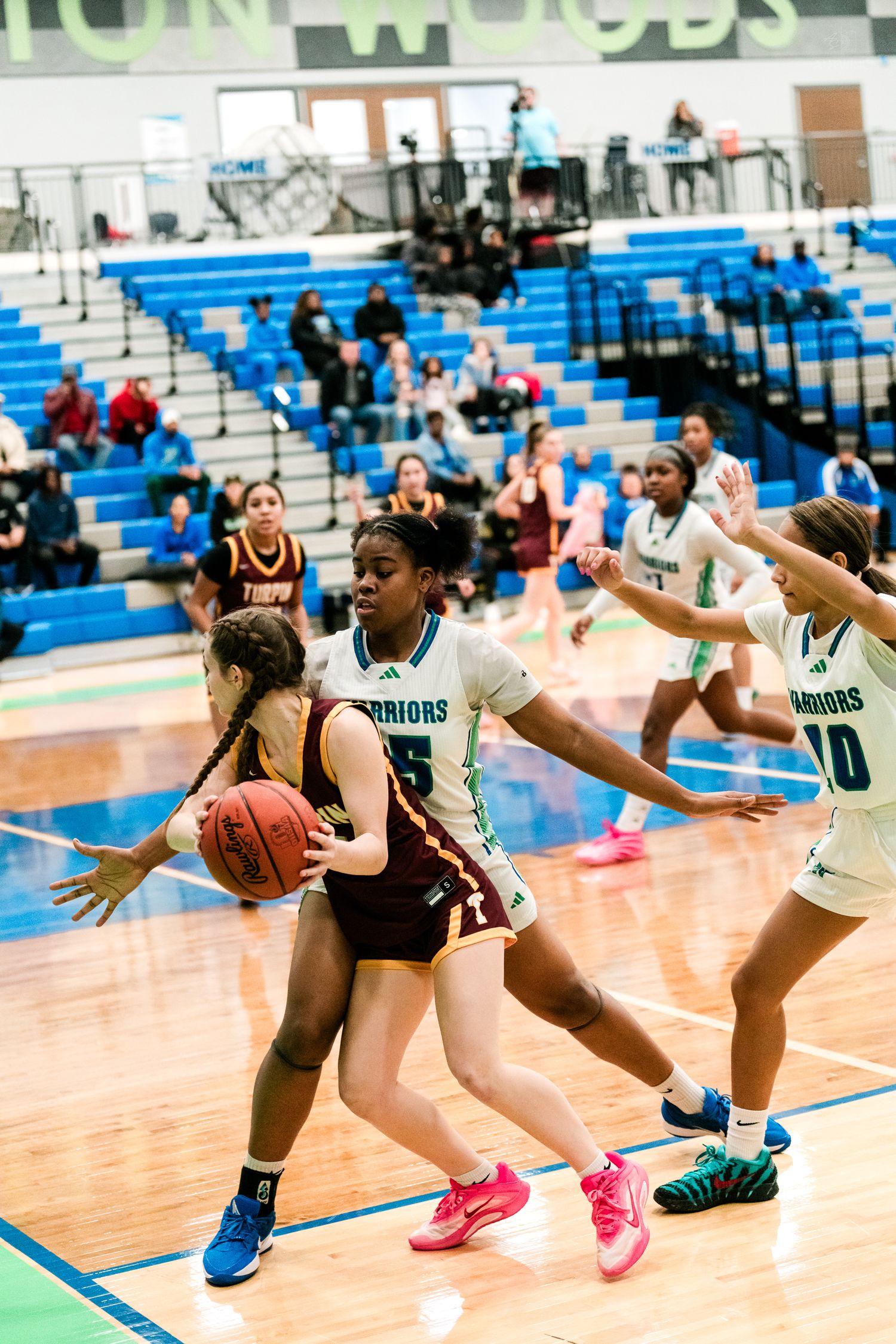 Warriors defenders pressure a Turpin player driving to the basket in a girls high school basketball game.