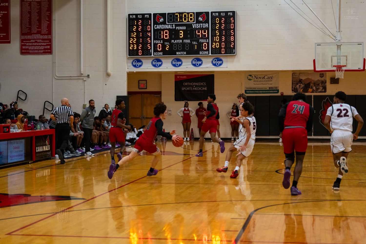 Princeton basketball players run plays during game with scoreboard showing close score overhead.
