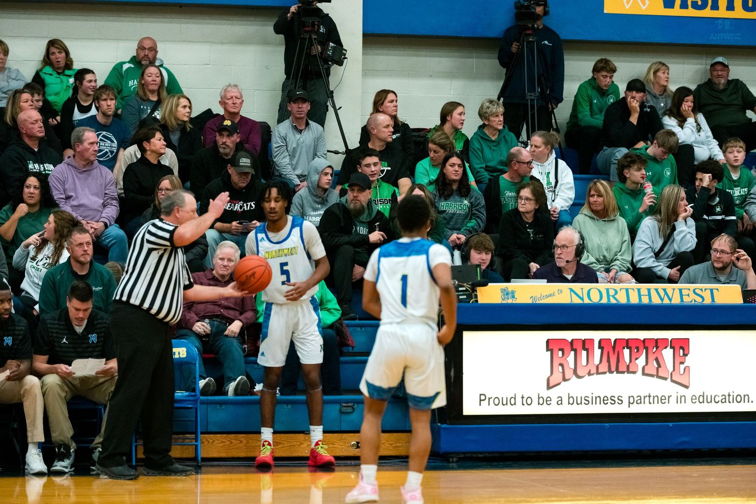 Basketball players in blue uniforms confer near scorers table during game.