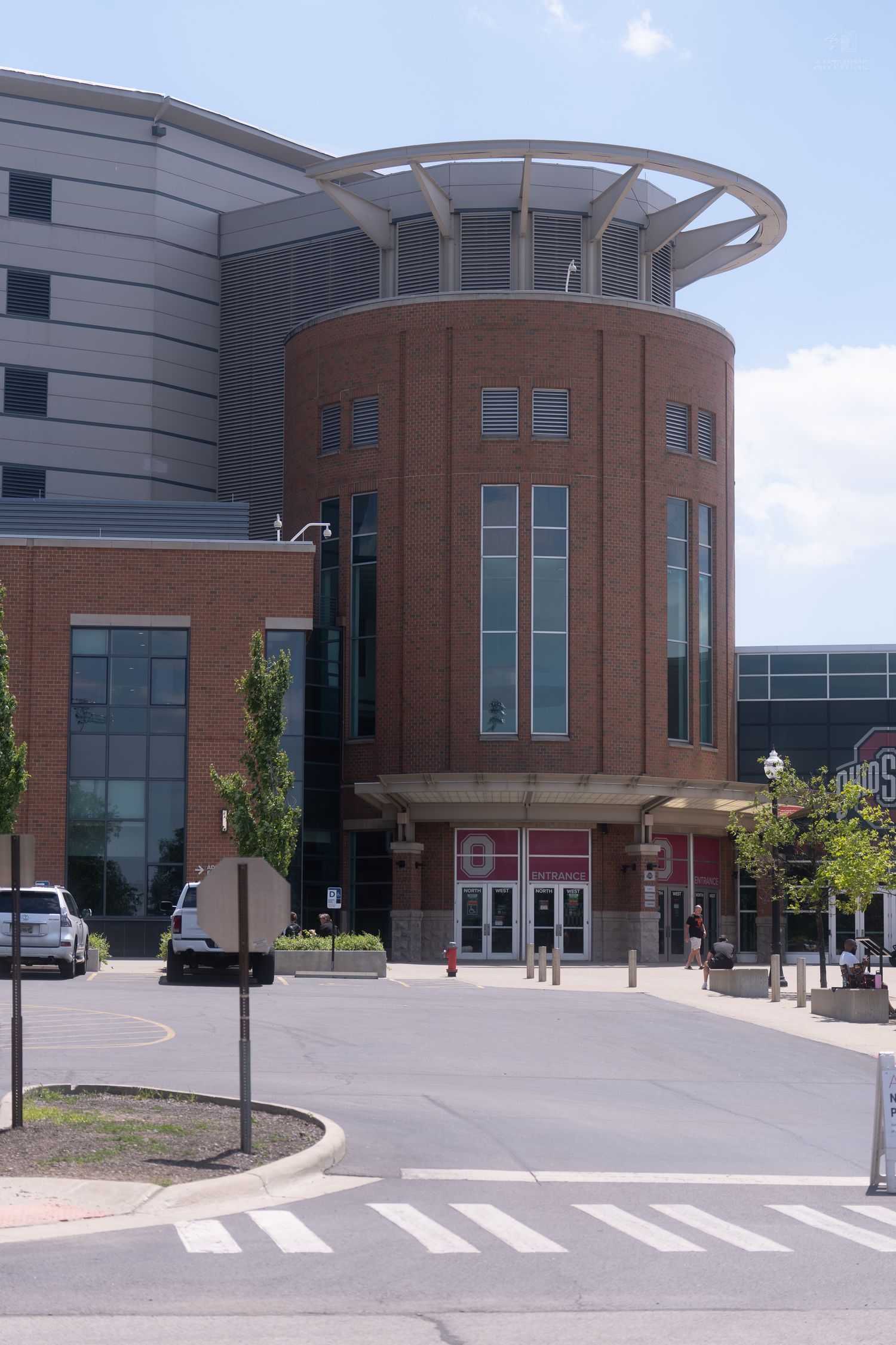 Modern brick and glass Ohio State University sports facility entrance with circular tower architecture.