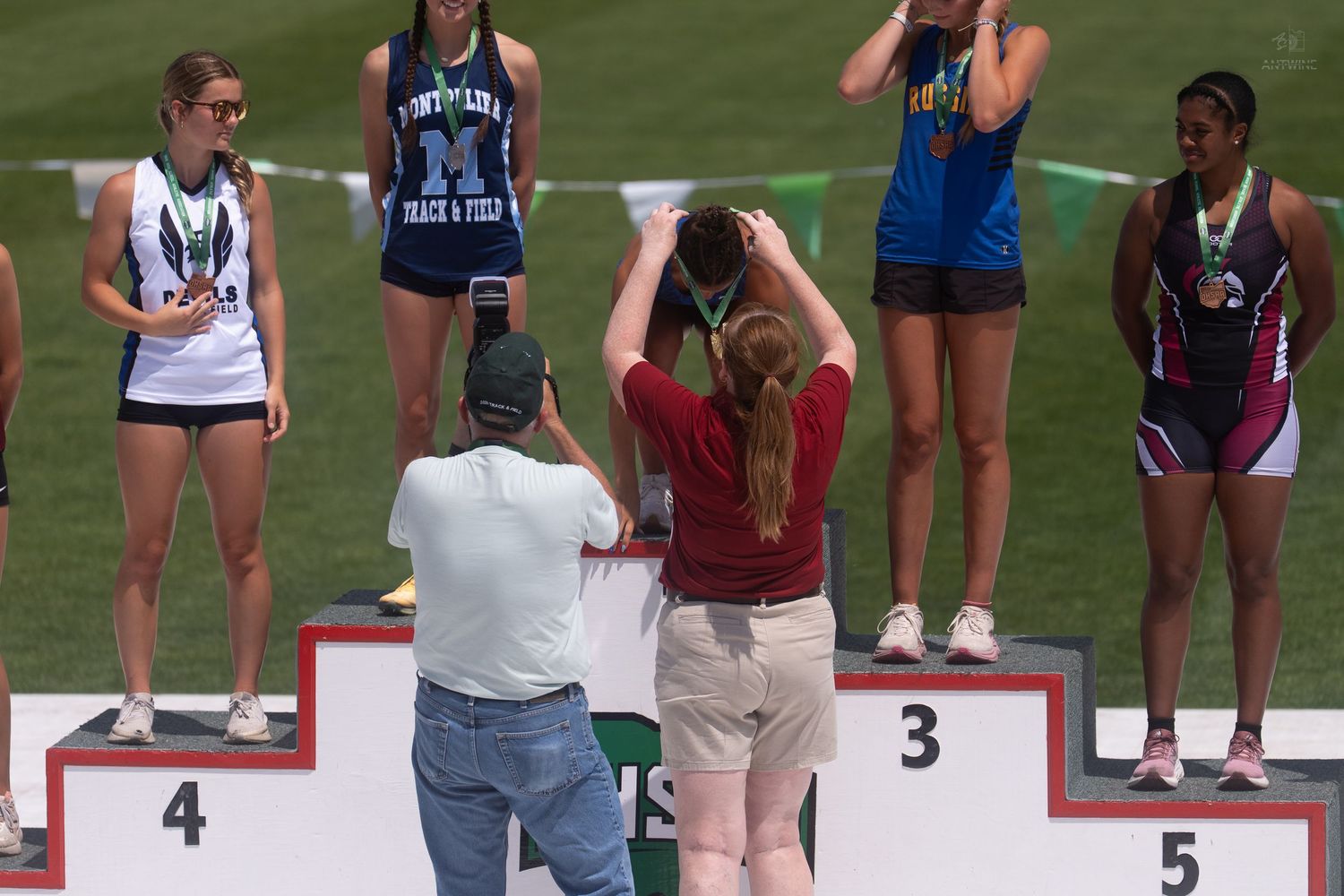 Girls stand on numbered podium positions at OHSAA state track and field awards ceremony.
