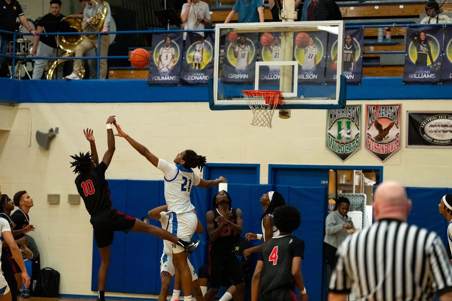High school basketball player number 21 in blue attempts a layup over a defender during a gymnasium game.