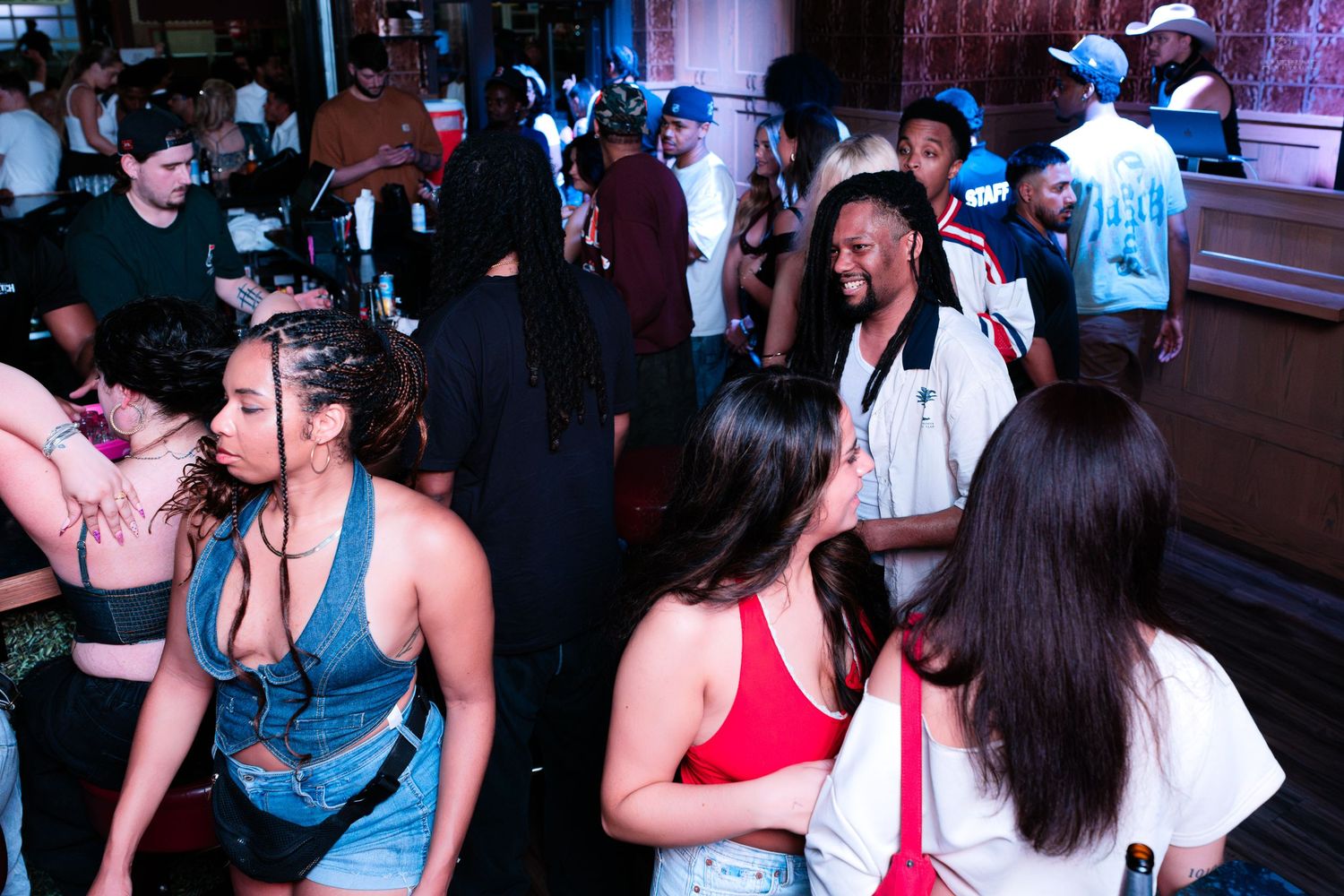 Energetic crowd mingling and dancing at a packed nightclub party.