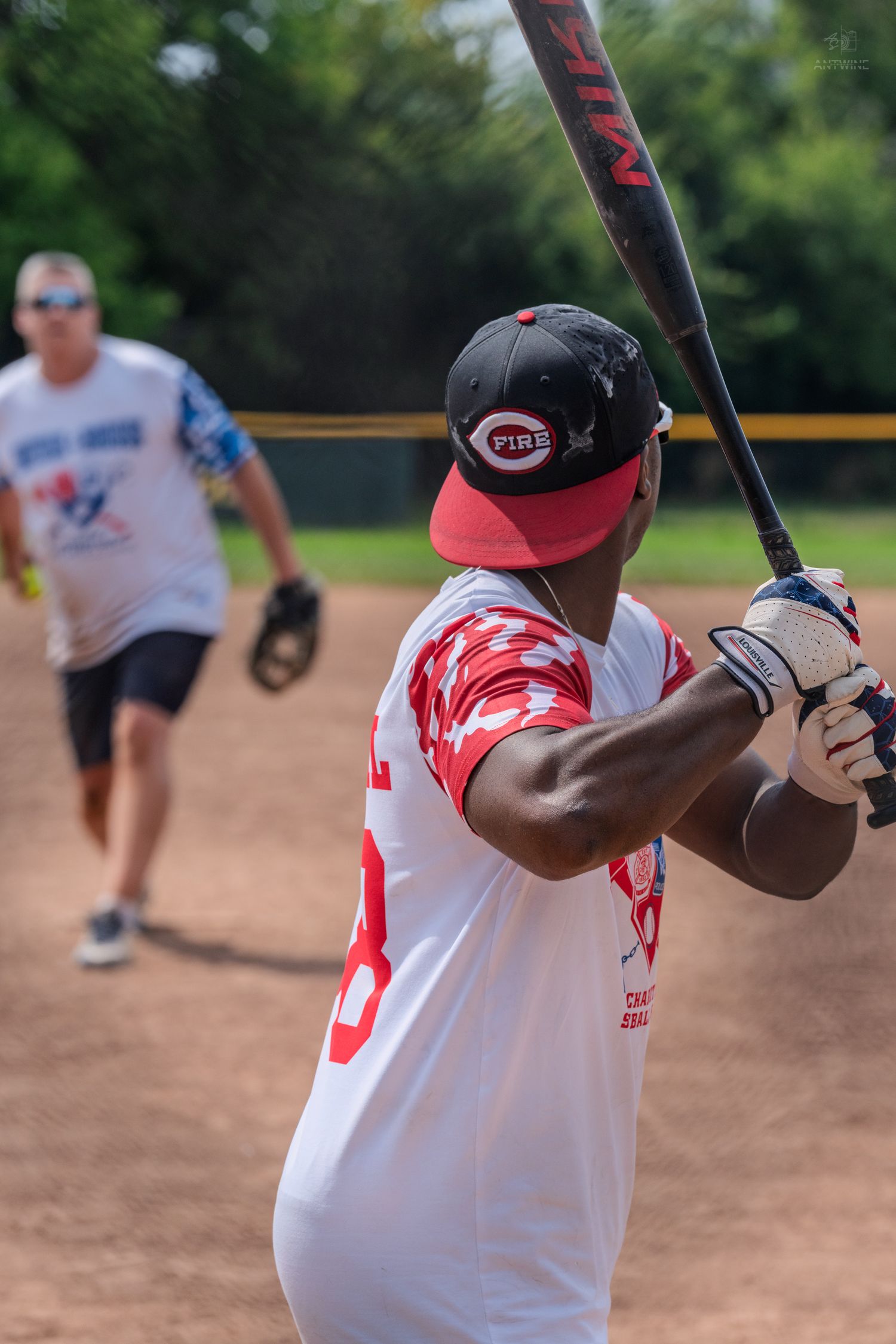 A batter wearing a Cincinnati Reds cap readies his swing during a Battle of Badges softball game.
