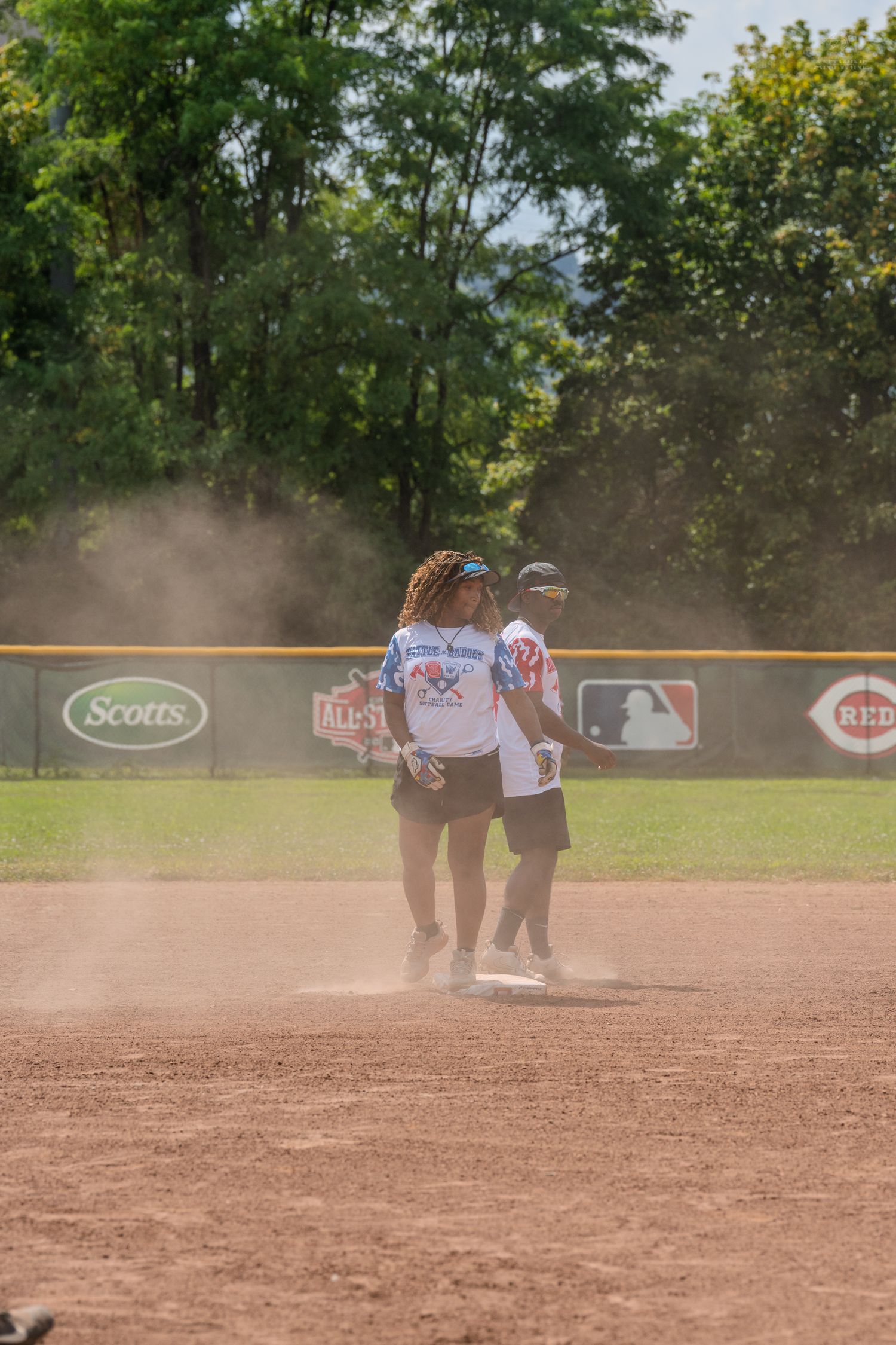 Players standing on baseball diamond during sunny outdoor softball game.