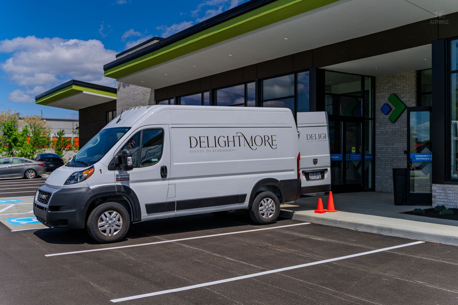 White Delightmore delivery van parked outside a modern commercial building on a sunny day.