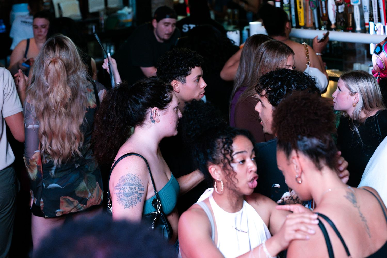 Diverse group of people socializing and mingling at a lively indoor bar or nightclub event.