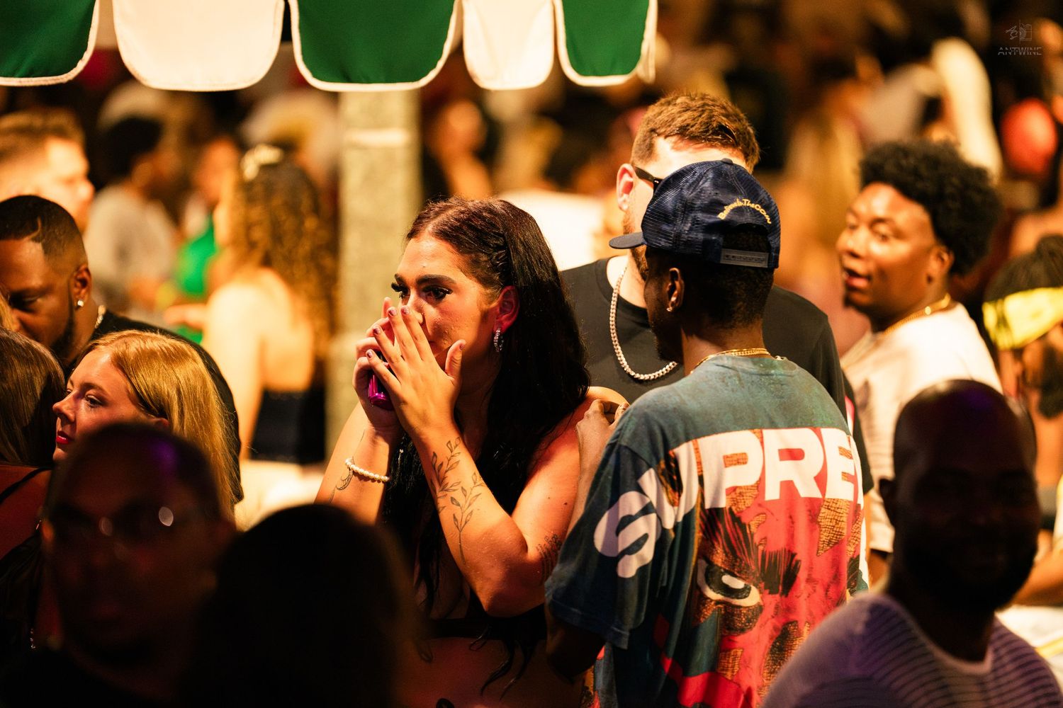 Crowd of people socializing at an outdoor nighttime event under warm lighting.