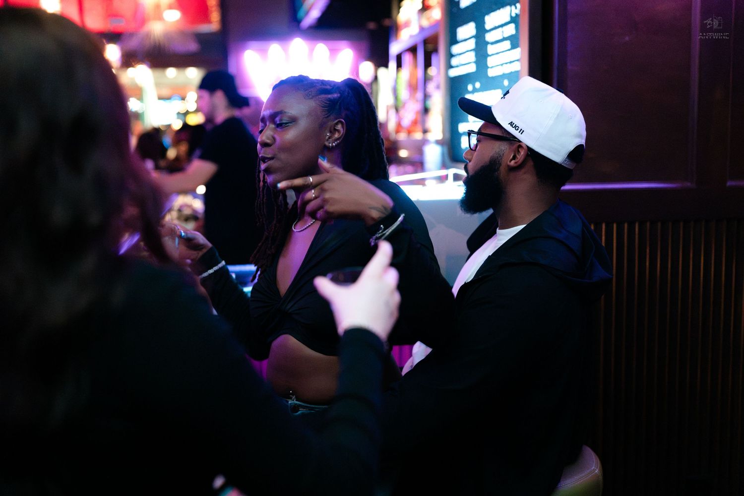 Couple having an intimate conversation in a colorful nightclub setting.