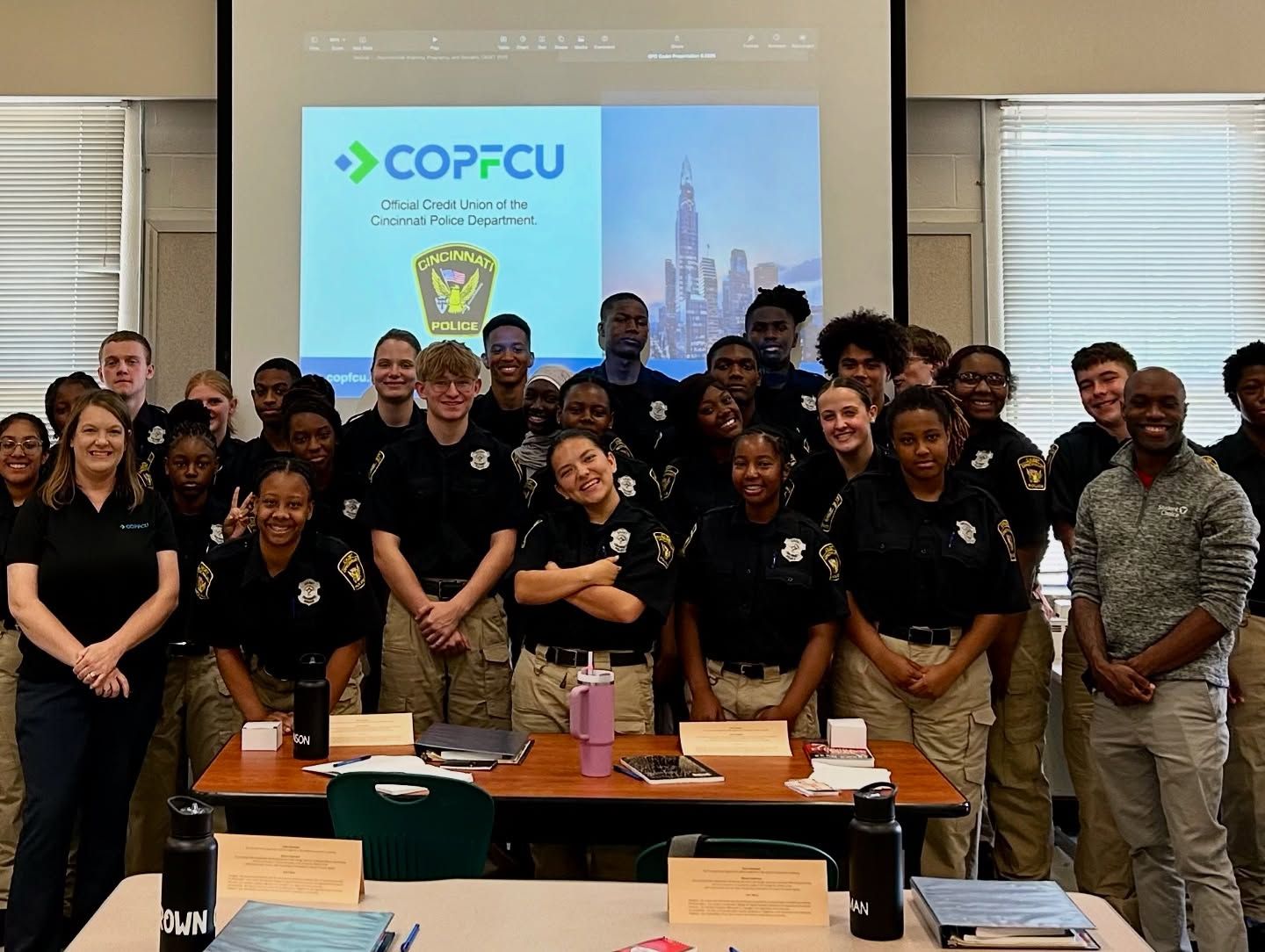 Large group of students and staff posing indoors in front of a COPFCU Chicago Credit Union presentation screen.
