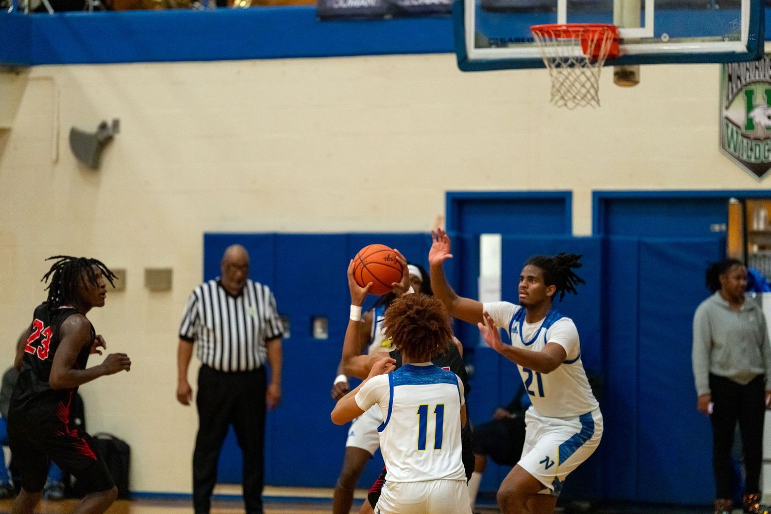 Female basketball players compete for a rebound near the hoop during a high school basketball game.