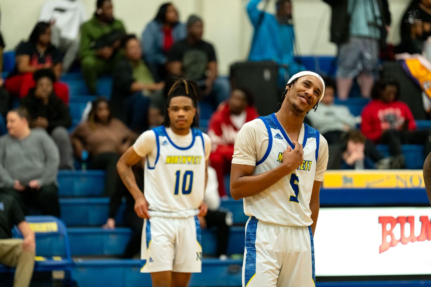 Two high school basketball players in blue and white uniforms stand on the court during a game.