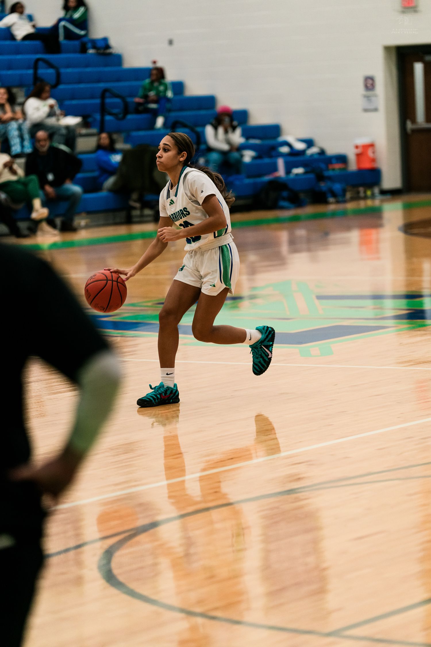 Warriors girls basketball player dribbles the ball down the court during a home game.