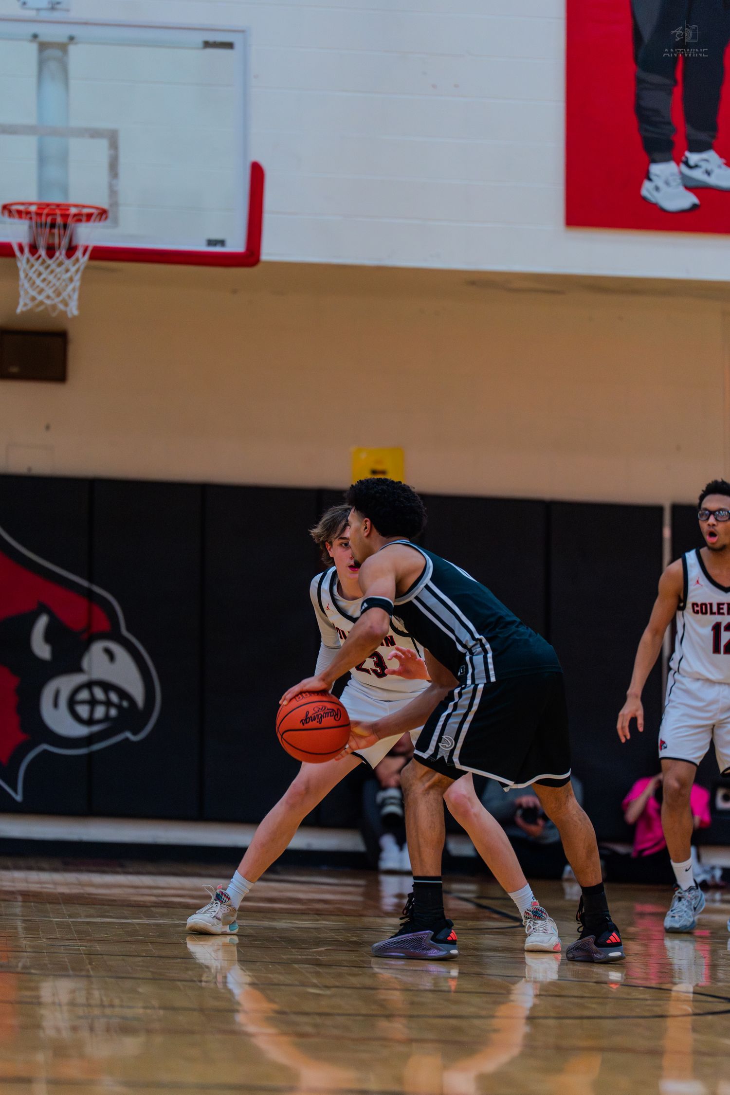Two high school basketball players battle for possession during an intense indoor game.