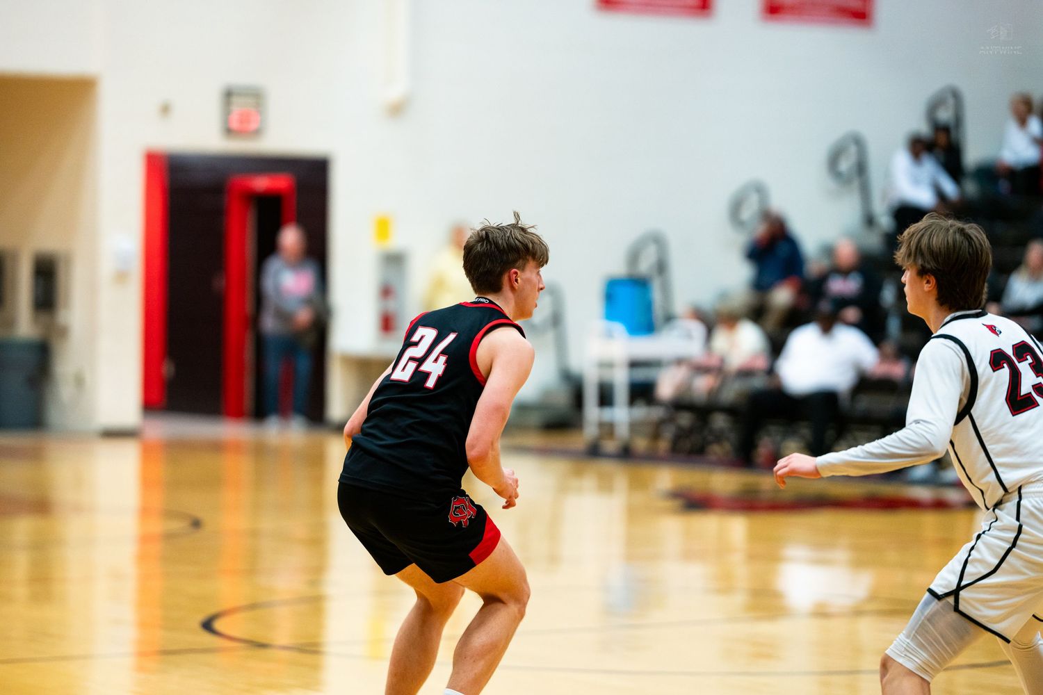 Player number 24 in a black jersey defends against an opponent during a youth basketball game.