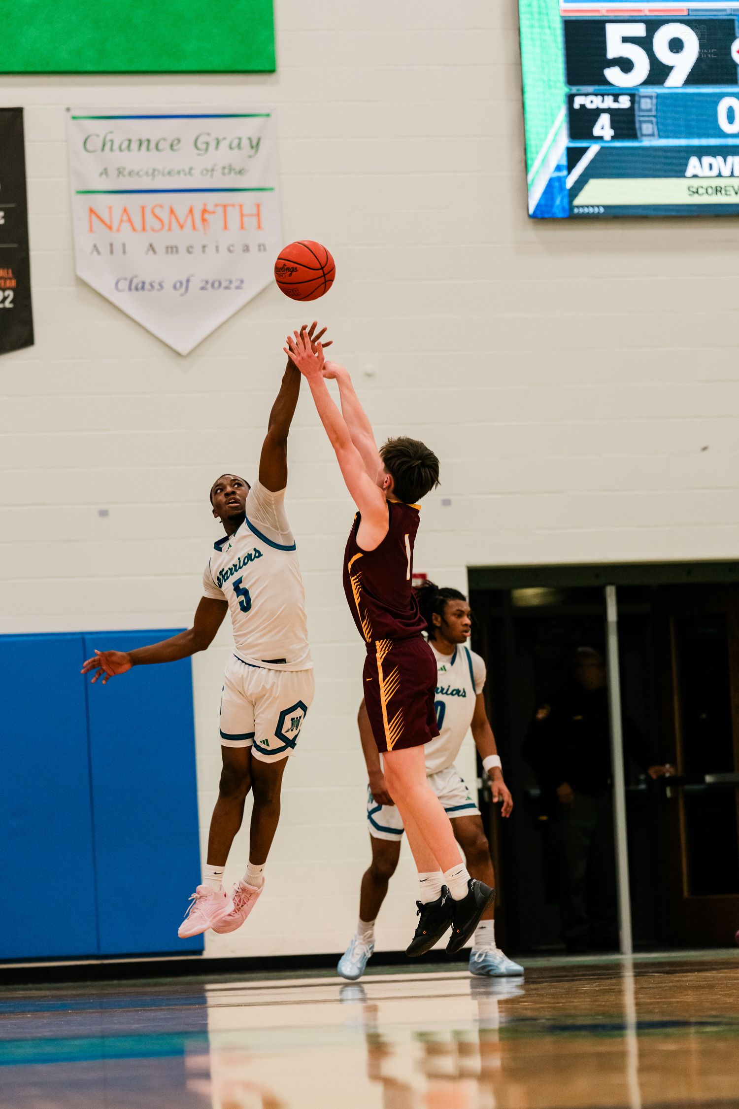 A Winton Woods player leaps to tip the ball against a Turpin opponent near the Naismith All American banner.