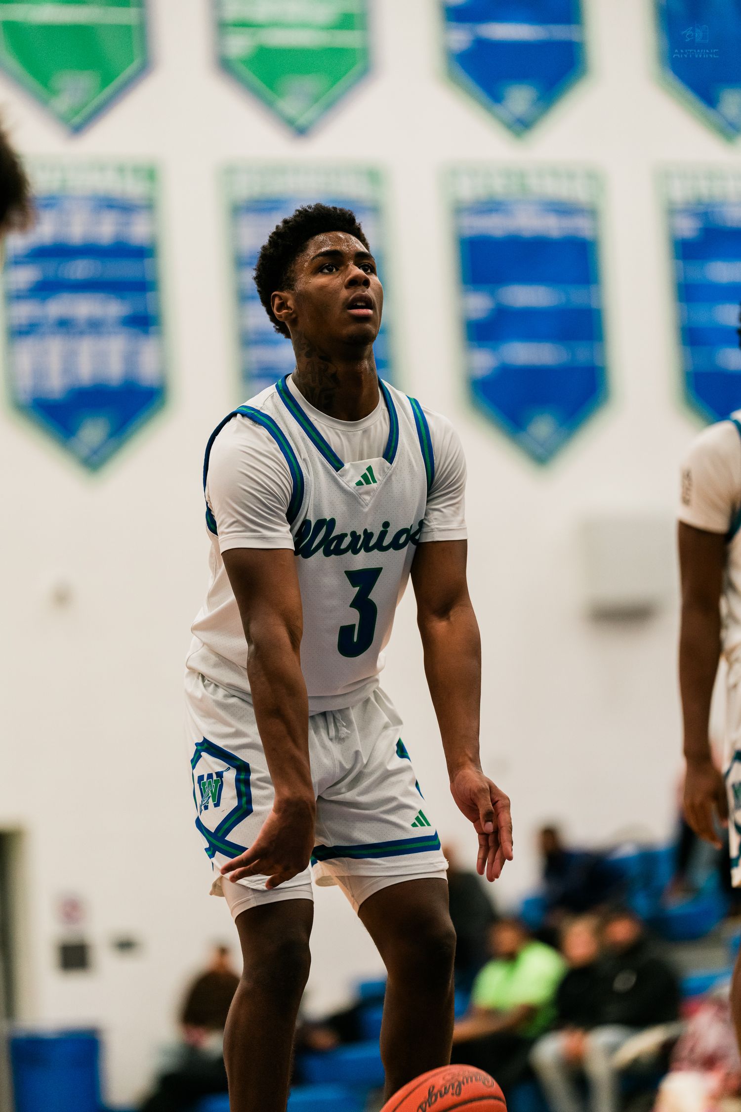 Warriors player #3 looks up toward basket during indoor high school basketball game.