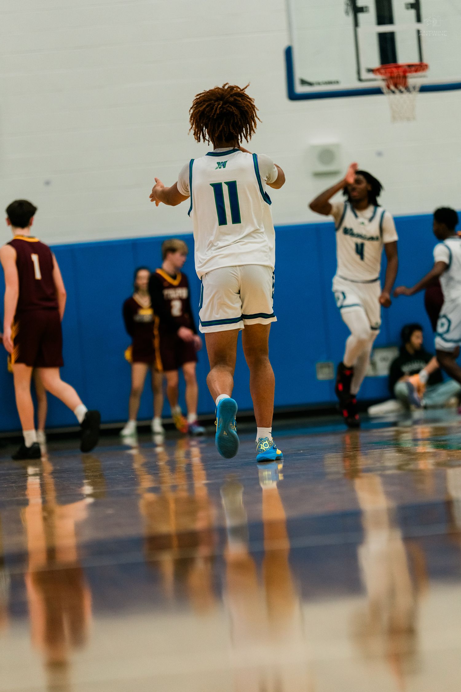 Xavier Warriors #11 jumps in celebration as teammate #4 reacts after a successful play in a gym.