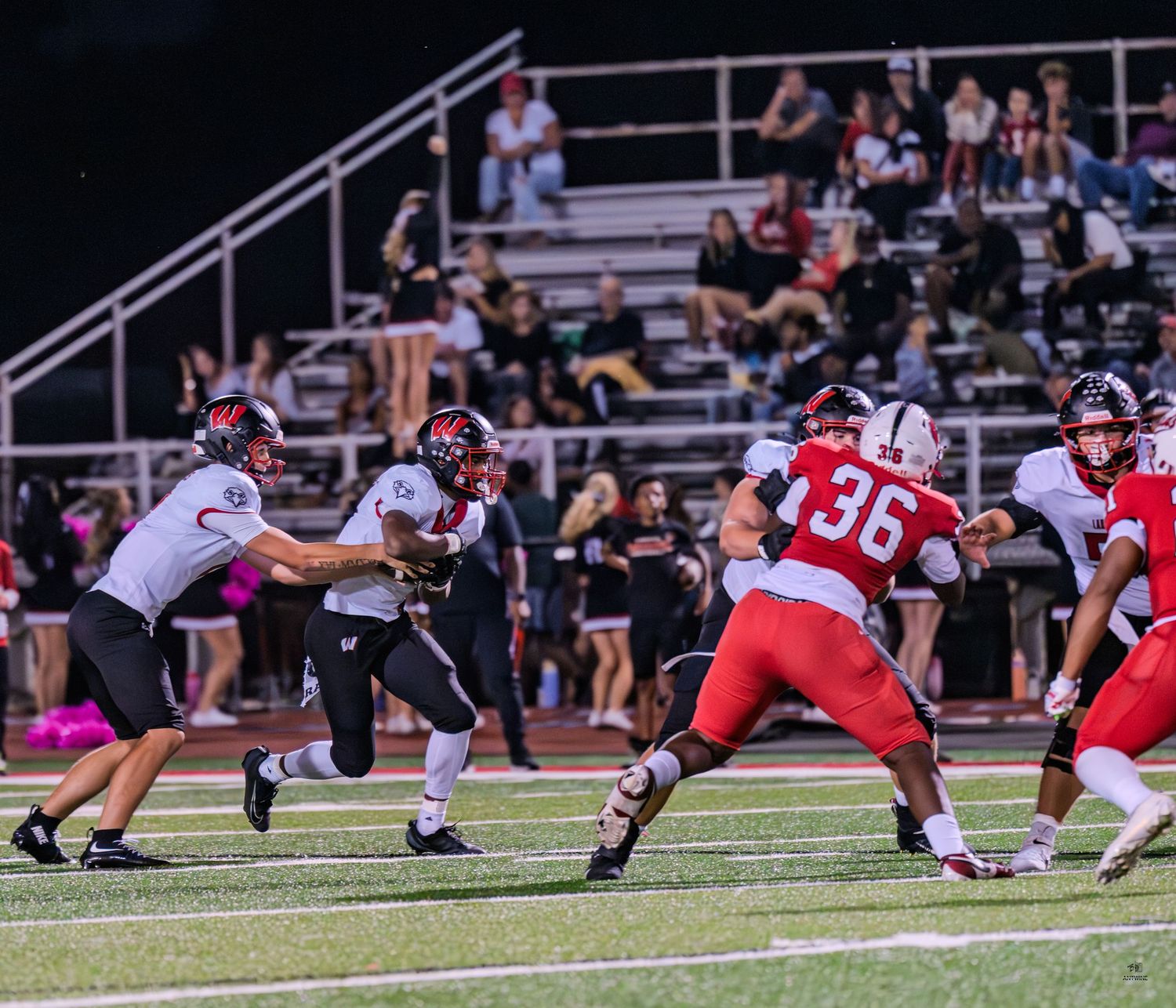 Football players in red and white uniforms engage in a play near the line of scrimmage.