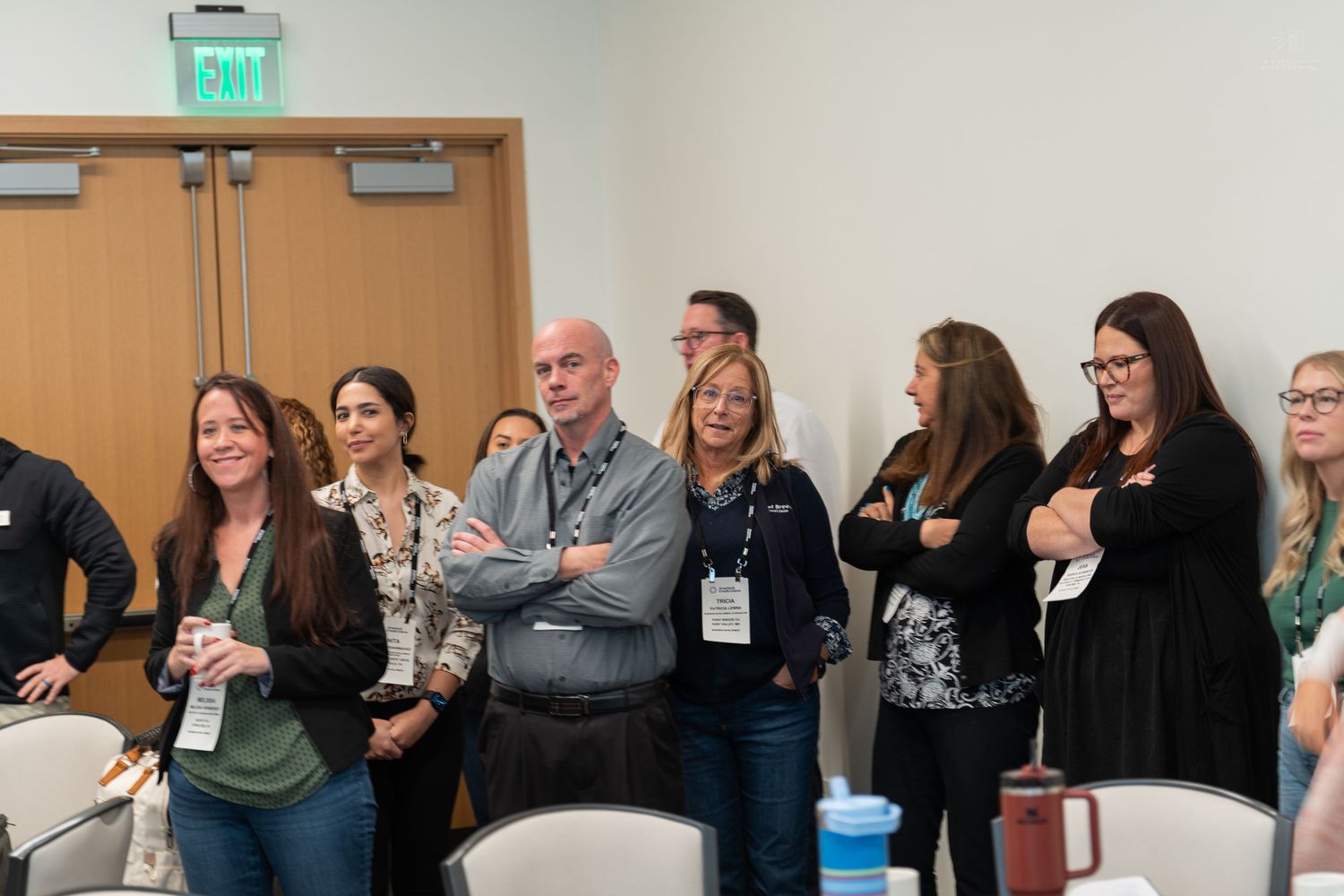 Group of professionals standing and listening attentively at an indoor conference event.