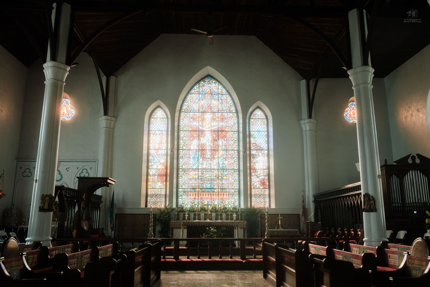 Beautiful Gothic church interior featuring ornate stained glass windows above a decorated altar.