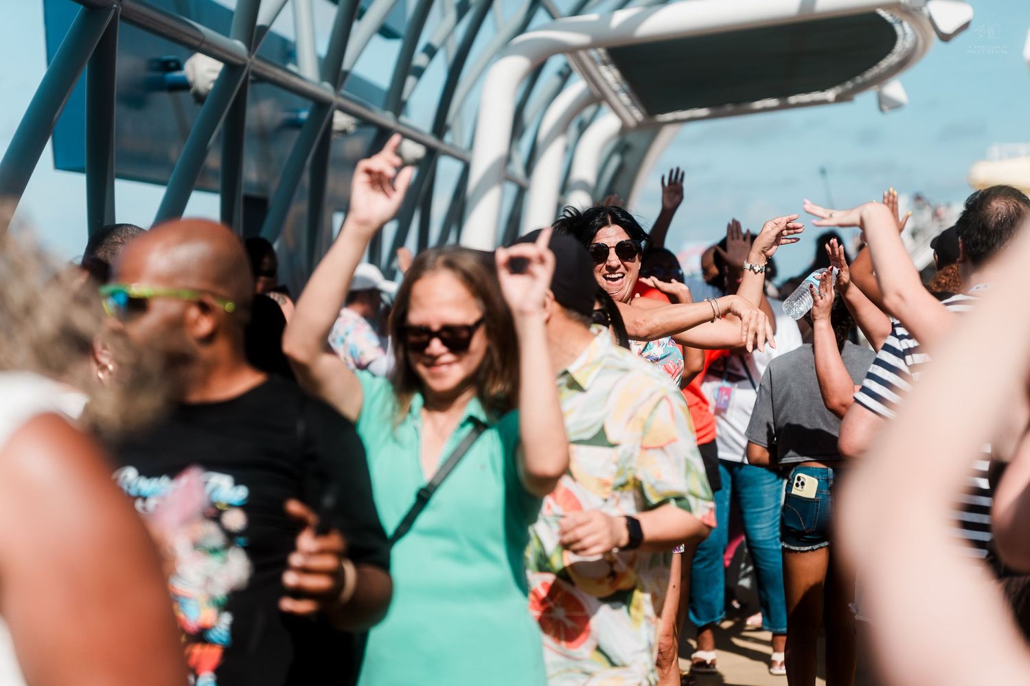 Happy people dancing and celebrating on a sunny cruise ship deck.