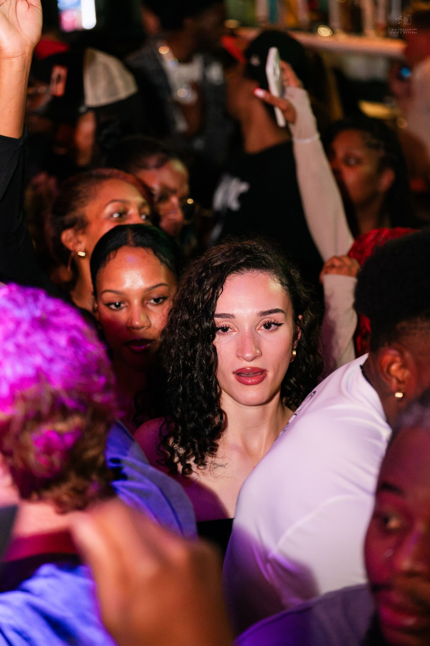 Diverse crowd of people dancing and socializing at a lively nightclub party event.