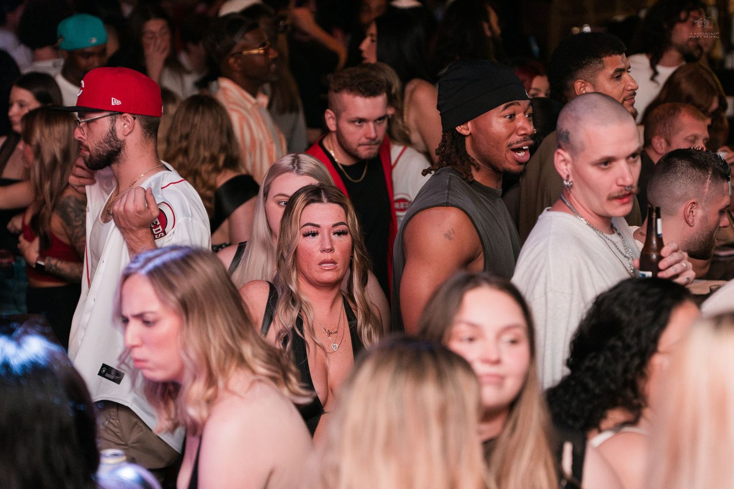 A diverse crowd of young adults mingles at a vibrant, packed nightclub event.