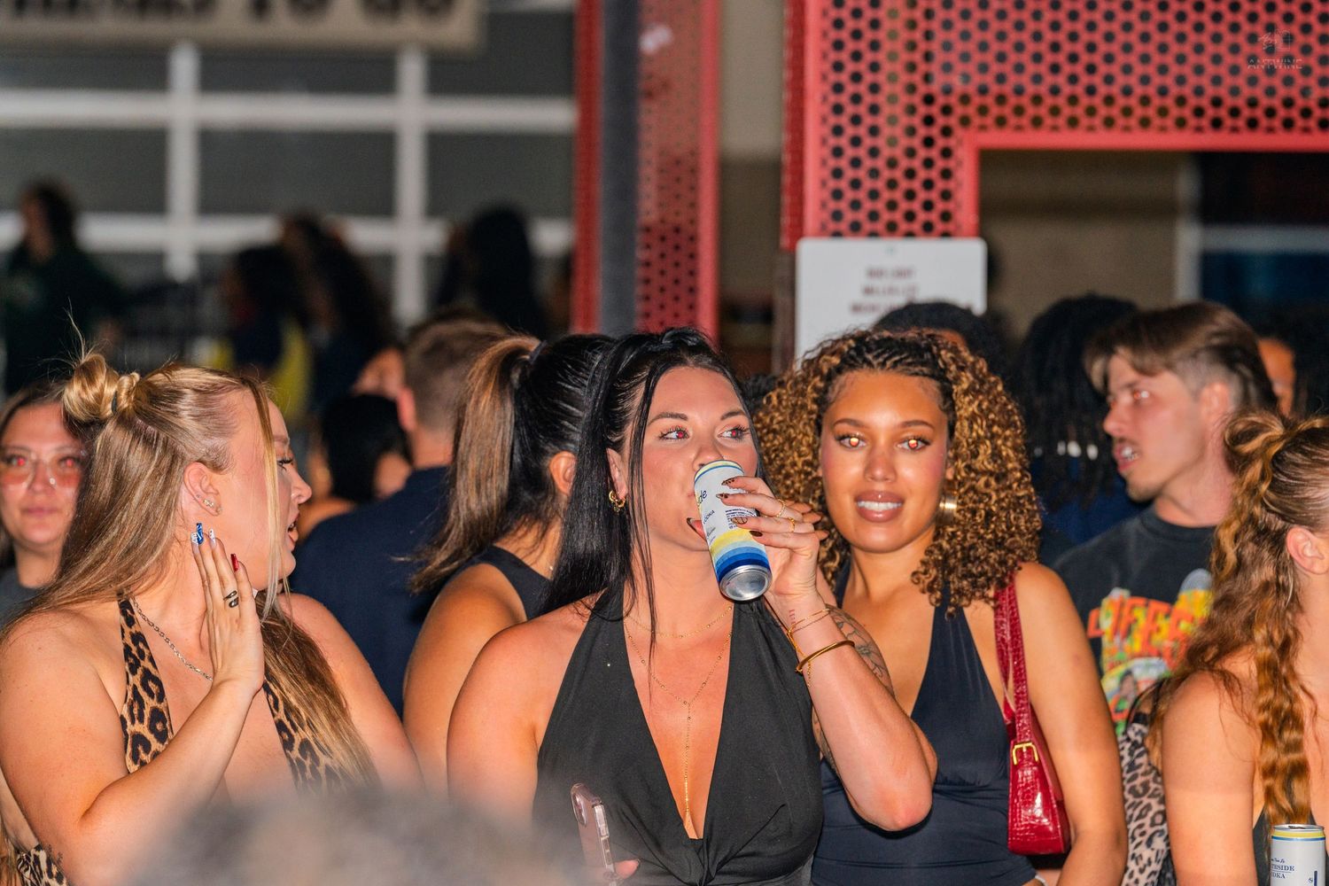 Women in black outfits socializing at a crowded nightclub event.