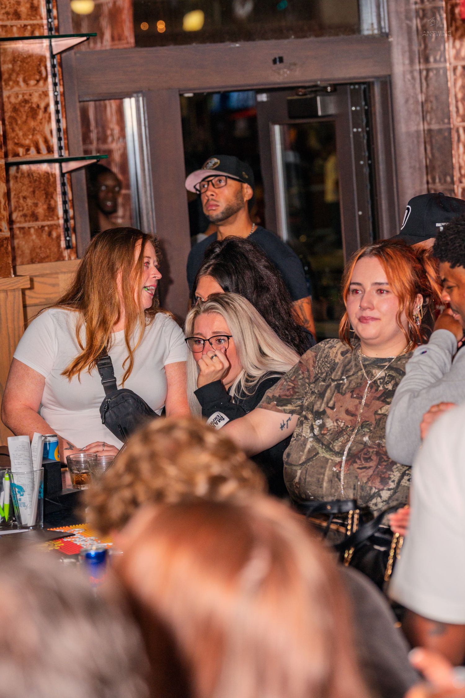 Group of women laughing and socializing at a crowded indoor bar or nightclub event.