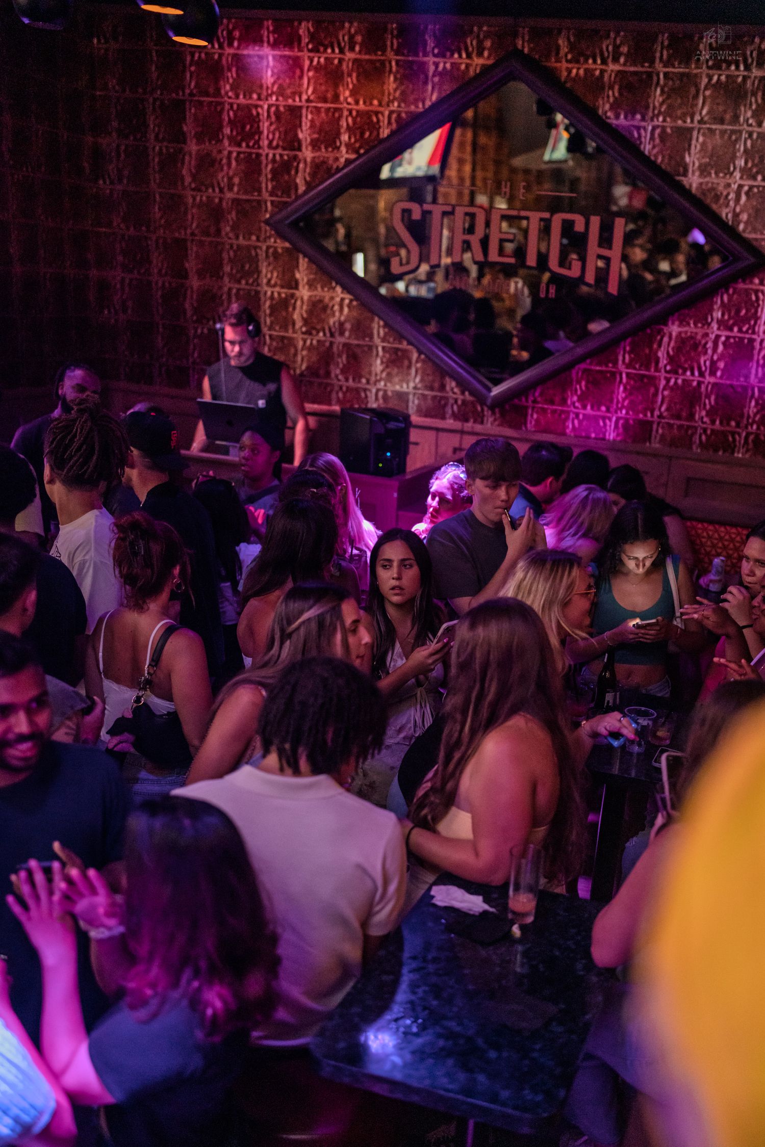 Groups of people socializing under purple lights near the Stretch bar sign.