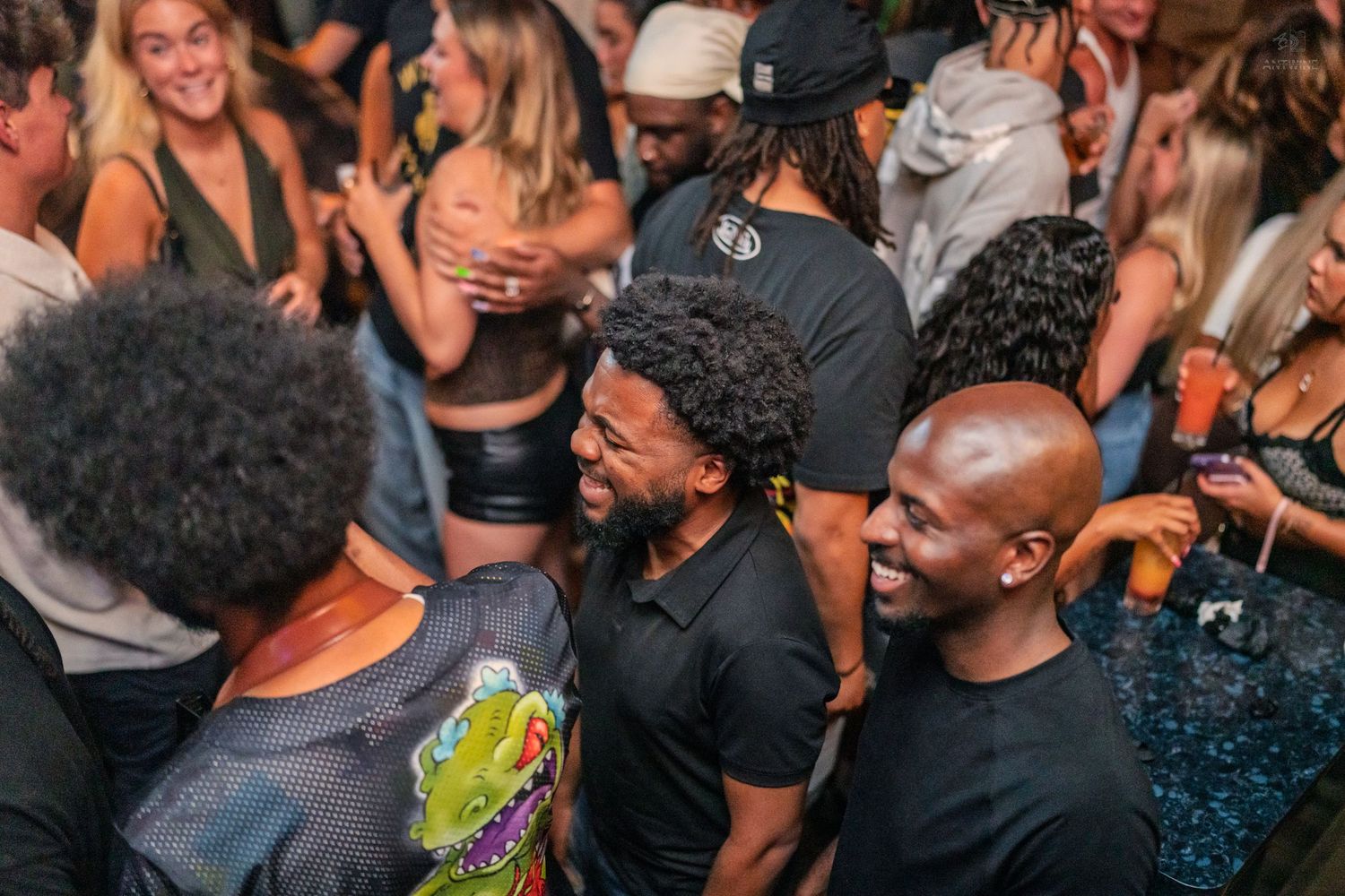 Smiling friends laughing together in a packed nightclub during a fun party event.