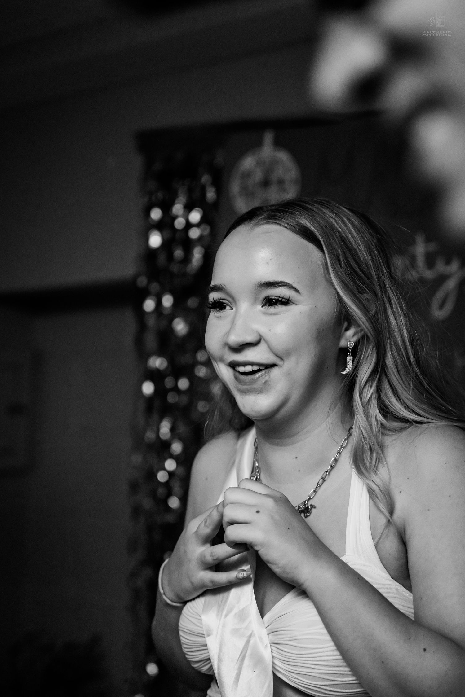 Black and white portrait of smiling blonde woman in white top at a festive birthday party.