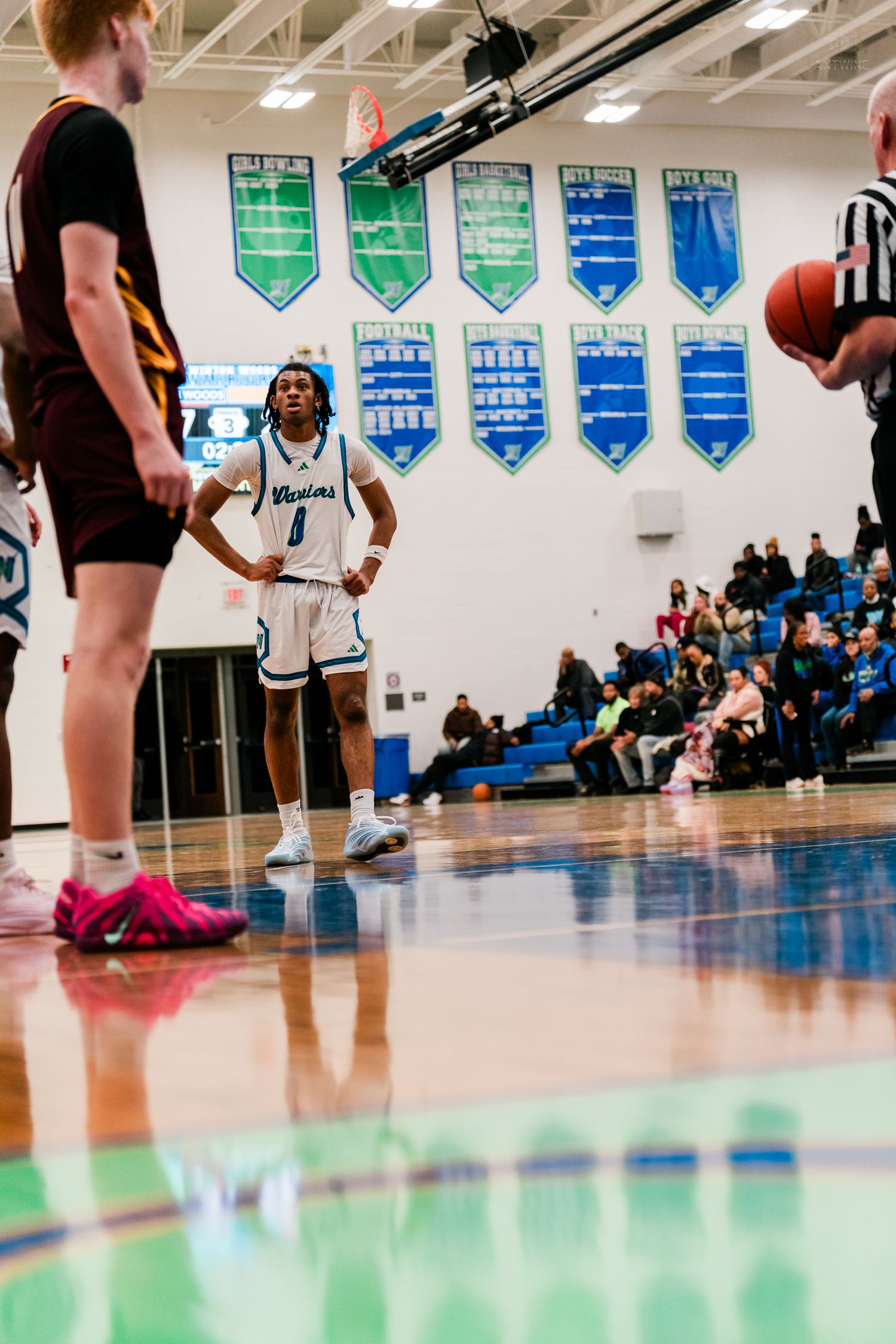 Warriors basketball player #1 stands at free throw line in blue and white gym.